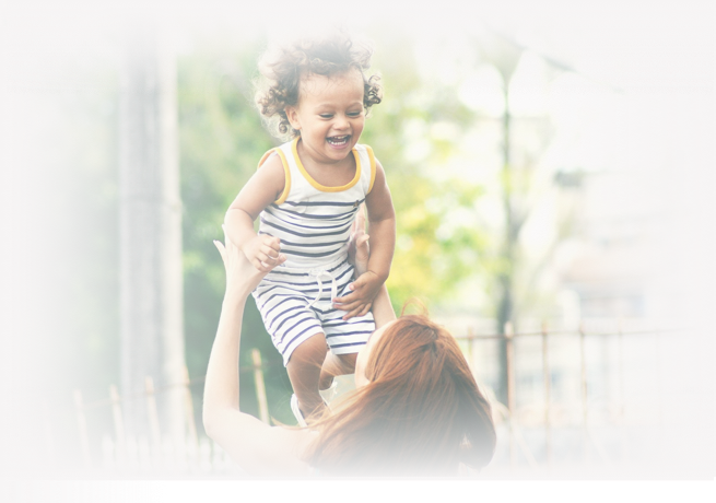 A mother playing with her toddler outdoors.