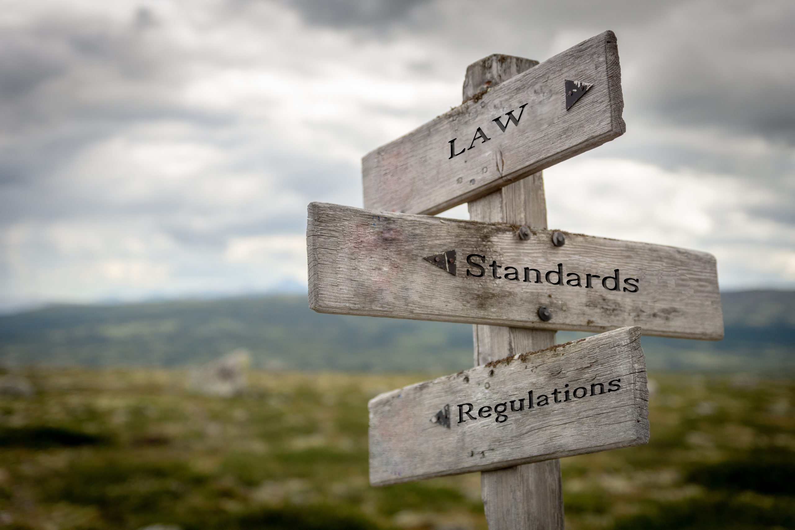 Law, standards and regulations text on wooden road sign outdoors