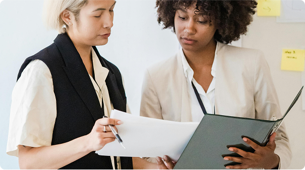 Two women reading documents in a binder