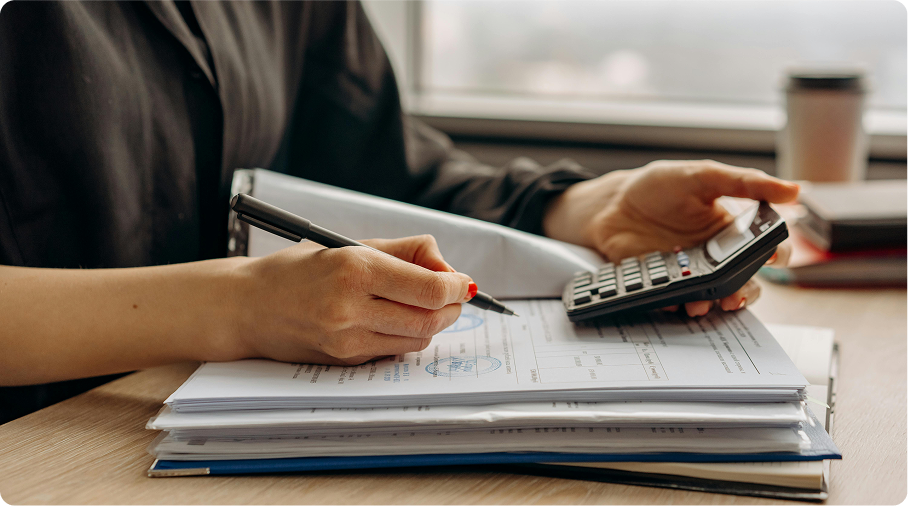 A person using a calculator and reviewing spreadsheets