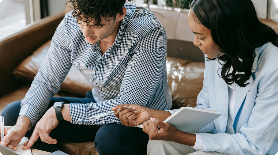 Two people sitting on a couch reviewing documents in their booklets.